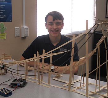 High school student smiling in front of his project