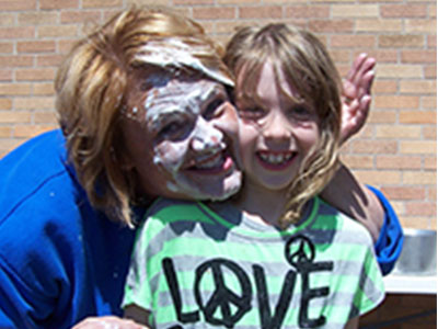 lady with cream on her face hugging student